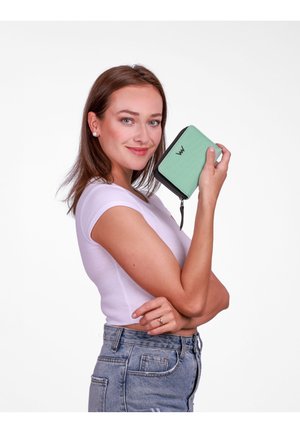 Mint green wallet with a textured finish and black zipper. Features a logo on the front and is held in a hand against a white background.