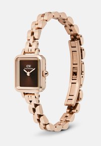 Montre pour femme Daniel Wellington en or rose avec un cadran rectangulaire marron foncé et un bracelet en métal à maillons ouvert.