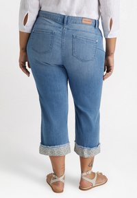 Jeans de mezclilla azul claro cortos con bordes deshilachados y puños con estampado floral, que incluyen dos bolsillos traseros y una etiqueta de cuero de marca.