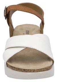 White leather sandal with cross straps, brown adjustable ankle strap, cork midsole, and a textured beige insole. Lightweight design.