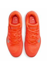 Helle orange Sport Schuhe mit einem strukturierten Mesh-Obermaterial, flachen Schnürsenkeln und einem silbernen Swoosh-Logo an der Seite. Gemusterte Akzente an der Sohle.