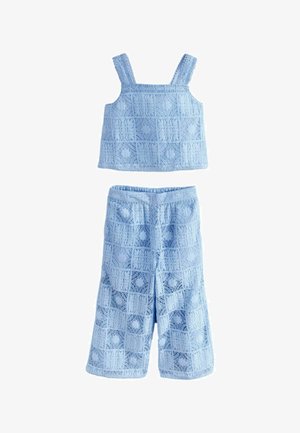 Svetlomodrý krajkový crop top bez rukávov a súprava s širokými nohavicami so štvorcovými a kvetinovými vzormi.