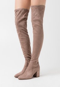 Botas de ante taupe hasta la rodilla, con puntera afilada, tacón cuadrado y diseño ajustado. Textura suave con un acabado liso y sin herrajes visibles.