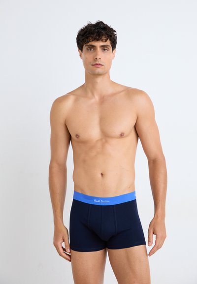 Slip in cotone morbido di colore blu navy con un elastico in vita blu che presenta il nome del marchio "Paul Smith" in bianco. Texture liscia, design aderente.