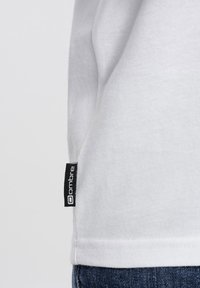 Weißes Baumwoll-T-Shirt mit einem Seitennackenlabel der Marke "ombre". Der Stoff wirkt weich und hat ein einfaches Design sowie eine moderne Passform.