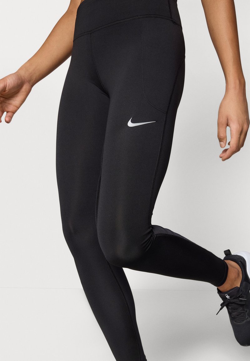 Leggings deportivos negros hechos de material elástico, con un diseño ajustado y un pequeño logo blanco de Nike en el muslo.