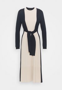 Gebreide jurk met lange mouwen; beige lijfje en donkere marineblauwe mouwen en taillekoord; heeft een ronde halslijn en maxi-lengte.