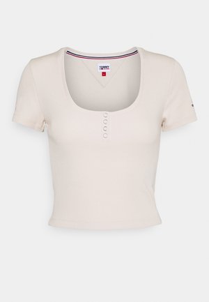 Kremfarvet kortærmet ribbet crop top med rund halsudskæring og fire små knapper under kraven, mærket Tommy Jeans størrelse small.
