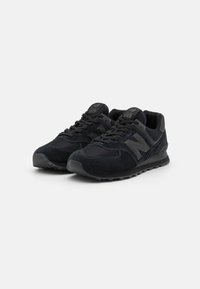 Schwarze Laufschuhe aus Wildleder und Netzmaterial, mit einem gepolsterten Schaft, flachen Schnürsenkeln und einer strukturierten Gummisohle. Logo an der Seite.