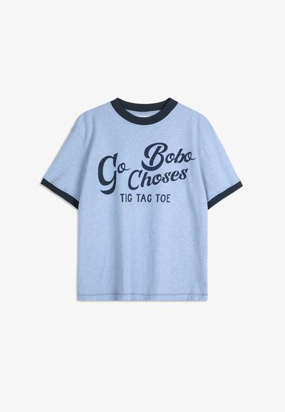 Světle modré bavlněné tričko s černým žebrovaným kulatým výstřihem. Na přední straně se nachází černý text "Go Bobo Choses Tic Tac Toe" v různých písmových stylech. Krátké rukávy.