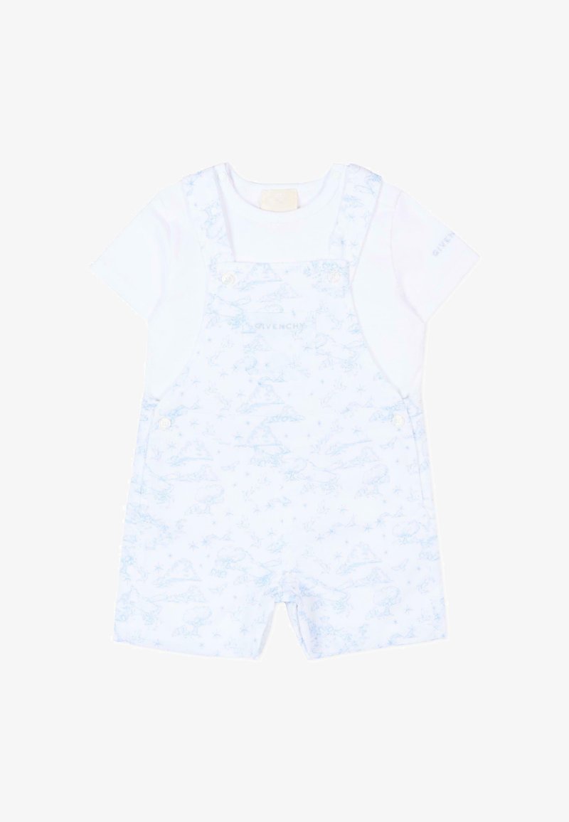 Chemise blanche à manches courtes associée à une salopette courte bleu clair à motifs, avec des boutons sur les bretelles et les côtés, conçue pour les tout-petits.