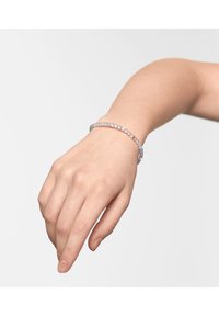 Zilveren kralenarmband om een pols. De kralen zijn helder met een lichte iriserende glans, gerangschikt in een flexibele, cirkelvormige design.
