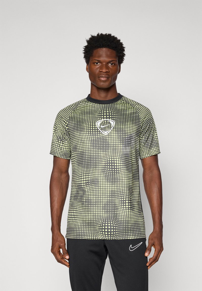 Camiseta deportiva de manga corta en verde y negro con un patrón de puntos, que presenta un cuello redondo y un logo de Nike en el centro frente.