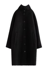 Svart oversized kappa med texturerad yta, hög krage, 6 framknappar och två sidofickor. Ärmarna är vida och något kortade.