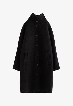 Black oversized coat with a textured finish, high collar, 6 front buttons, and two side pockets. Sleeves are wide and slightly cropped.