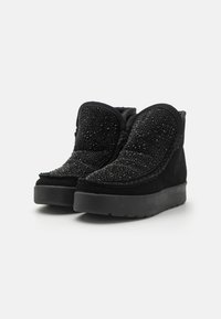 Botas de ante negro con un upper texturizado adornado con cuentas, un forro de piel sintética y una suela gruesa de goma negra.