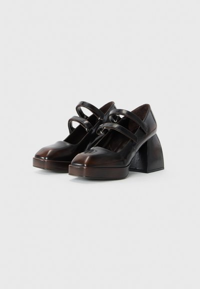 Chaussures à plateforme en cuir verni marron avec deux brides autour de la cheville et un talon carré. Texture lisse et design à bout arrondi.