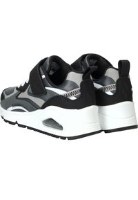 Scarpe sportive nere e grigie con tomaia in rete, cinturino in Velcro, colletto imbottito e intersuola bianca con unità ad aria. Suola testurizzata per una presa migliore.