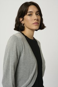 Grey open-front cardigan with a soft texture and slight shimmer, paired with a black top. Features a relaxed fit and draped sleeves.