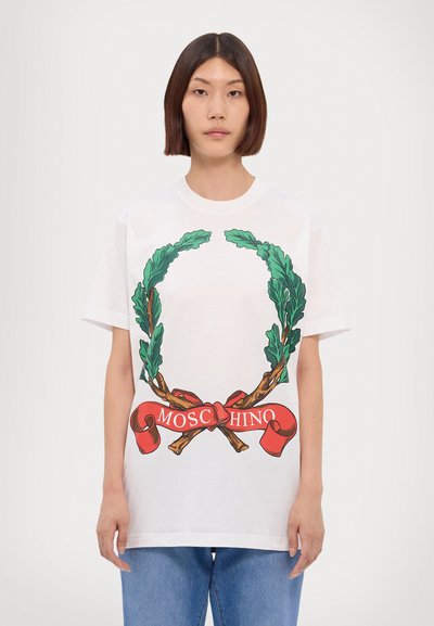 Bílá bavlněná tričko s designem zeleného listového věnce a červenou stuhou s textem "MOSCHINO" v bílé barvě, uvolněný střih, krátké rukávy.