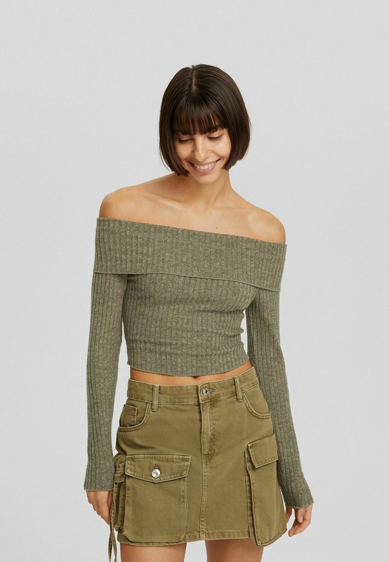 Top off-shoulder a coste verde oliva con maniche lunghe e design aderente, abbinato a una mini gonna in stile cargo coordinata con tasche.