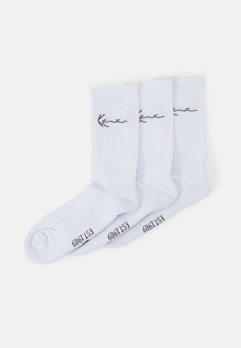 Trois paires de chaussettes blanches avec une texture côtelée, présentant un logo noir brodé et des chiffres sur la semelle. Tissu doux et léger.