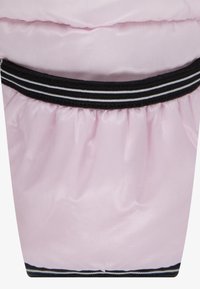 Rozā polsterēta auduma ar savītu tekstūru, augšējā malā ir melna elastīga josla ar baltām svītrām.