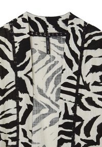 Baumwollschal mit Zebra-Muster in Schwarz und Weiß. Besitzt eine strukturierte Oberfläche und dekorative Nähte entlang der offenen Kanten.