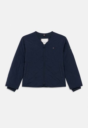 Tengerészkék steppelt cipzáras dzseki hosszú ujjakkal, kerek nyakkivágással, oldalzsebekkel és kis piros, fehér, kék logóval a mellkason és az ujjon.