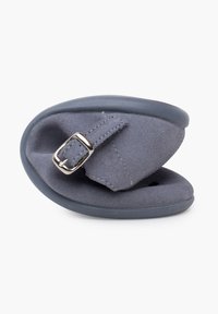Zapatilla de ante gris con suela de goma flexible, con una correa y hebilla de metal. El diseño es compacto y plegable para un fácil almacenamiento.
