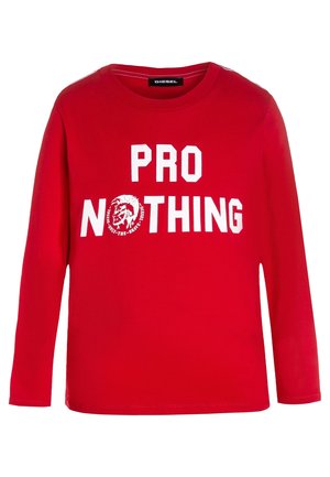 Czerwona koszulka z długim rękawem wykonana z bawełny, z białym napisem „PRO NOTHING” i grafiką głowy lwa. Standardowy krój z okrągłym dekoltem.