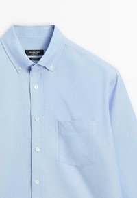 Light blue button-up shirt made of woven fabric, featuring a classic collar, front pocket, and standard button-down closures.