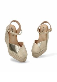 Sandalias de cuña beige con parte superior de tejido texturizado y acentos metálicos dorados, correa para el tobillo ajustable y plataforma de cuerda trenzada.