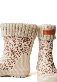 Stivali impermeabili a fantasia floreale con una base crema, polsino a coste di un beige chiaro e un'etichetta in pelle beige con la scritta "WHEAT". Suola in gomma testurizzata.