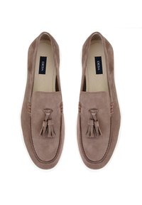 Braune Wildleder Slipper mit dekorativen Quasten, weißen Gummisohlen und Nahtdetails. Label im Inneren des Schuhs sichtbar.