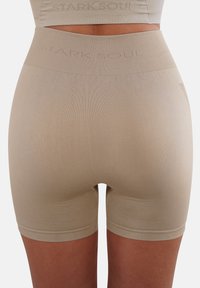 Beige High-Waist-Shorts aus glattem, dehnbarem Stoff mit enganliegendem Schnitt, ausgestattet mit einem breiten Bund, auf dem der Markenname eingeprägt ist.