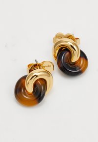 Gold and tortoiseshell twisted knot stud earrings with post backs, engraved with "kate spade" on the gold butterfly clutches.
