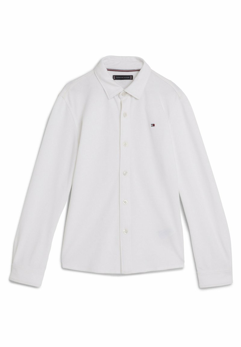 Camicia bianca a maniche lunghe con bottoni, realizzata in tessuto morbido, caratterizzata da un colletto classico, logo discreto sul petto e maniche con polsini standard.
