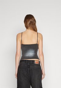 Metallic grå, åtsittande linne med tunna band, ribbat mönster och en kort längd, i kombination med svarta baggy cargo-byxor med en märkesplatta.