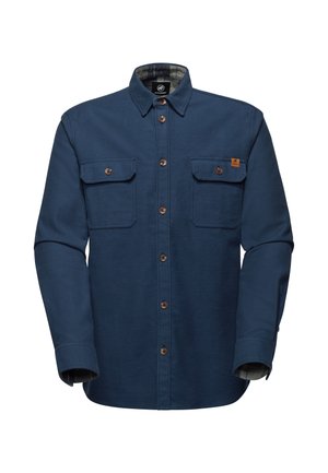 Camicia in flanella blu con due tasche sul petto, bottoni marroni e fodera a quadri visibile ai polsini. Presenta un colletto classico e un tessuto robusto.
