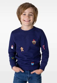 Marinblå sweatshirt med broderade festliga motiv: en mops, snögubbe, pepparkaka, godiskäpp, den heliga och ett inslaget paket.