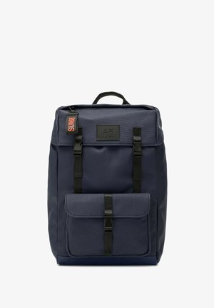 Zaino in tessuto blu navy con patta superiore, accessori neri, spallacci regolabili, tasca frontale e un'etichetta rossa con la scritta "SUN68."