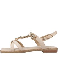 Sandalia beige con suela plana, con correas cruzadas, un acento joya y una correa trasera ajustable. Textura suave y diseño minimalista.