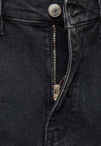 Jean en denim noir avec fermeture éclair argentée partiellement ouverte et bouton métallique visible à la taille.