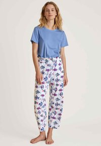 Lichtblauw T-shirt met korte mouwen, gecombineerd met pyjamabroek met elastische taille, met een kleurrijk vissenpatroon op een witte achtergrond.