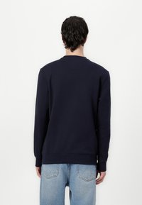Navy blue sweatshirt with long sleeves, crew neck, and ribbed cuffs and hem. Smooth, thick fabric with minimal stitching detail.