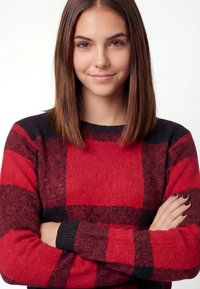 Red and black plaid sweater with a crew neckline, long sleeves, and textured fabric. Features bold block patterns and ribbed cuffs.