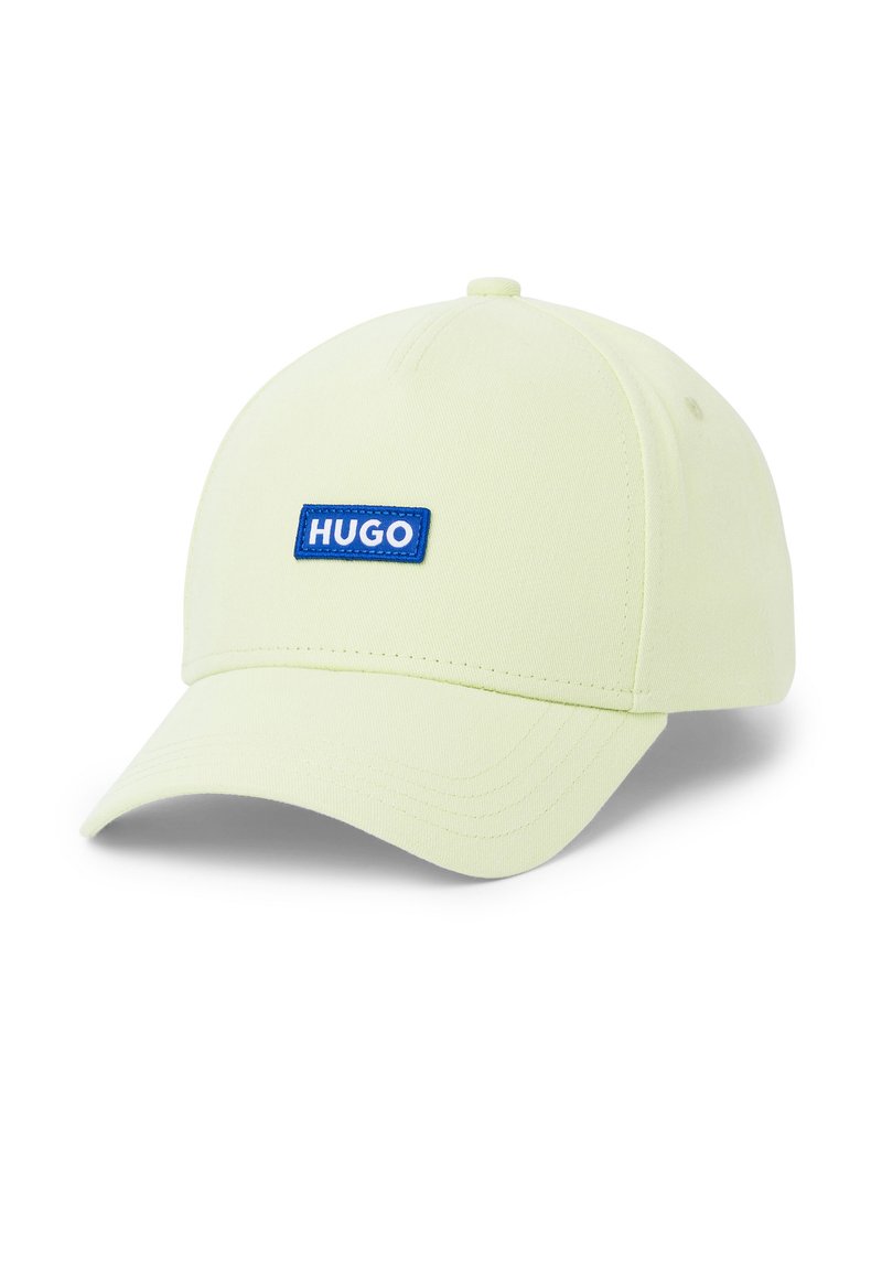 Cappellino da baseball verde chiaro in tessuto con visiera curvata. Presenta un patch rettangolare blu con il logo "HUGO" in testo bianco.