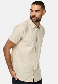 Kortærmet beige skjorte i let stof, med button-down krave og en enkelt brystlomme, i en afslappet pasform og tekstureret finish.
