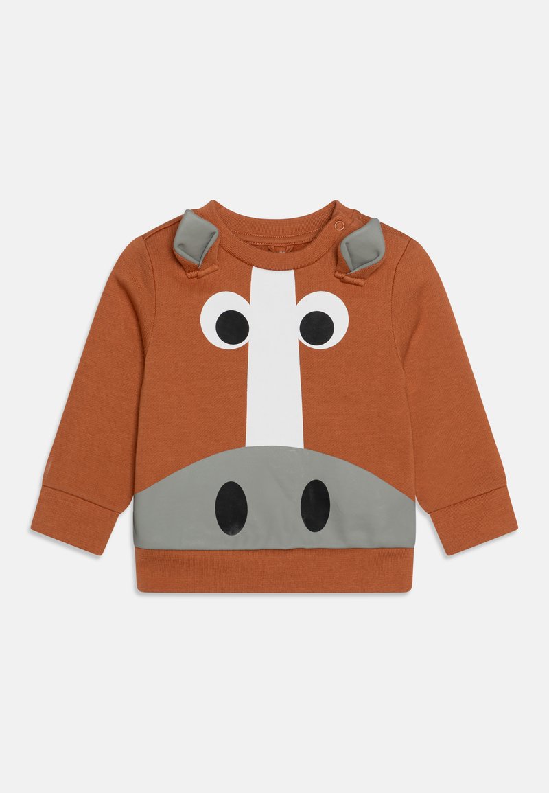 Oranžs džemperis ar zirdziņa dizainu; tam ir pelēki akcenti, lieli melni acu zīmuļi un plecu pogas. Mīksta tekstilizstrādājums ar strukturētu apdari.